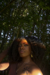 a woman is standing in a wooded area