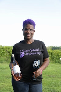 a woman with purple hair holding a bottle of wine