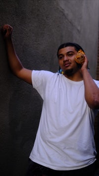 a man with dreadlocks leaning against a wall