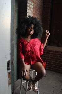 a woman with an afro sitting on a stool